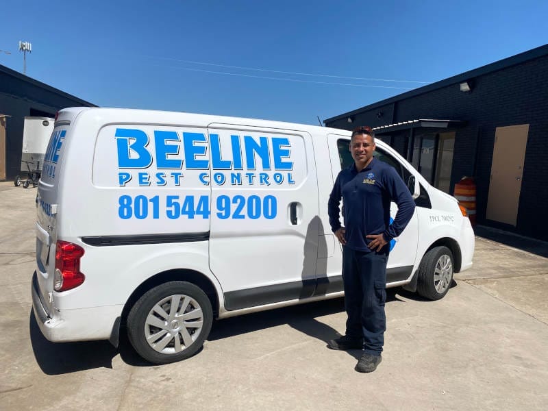 A Beeline Pest Control technician in front of van